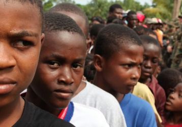 Haitian children surrounded by US military personnel 